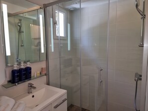 Une salle de bain moderne avec une douche à parois de verre, un lavabo blanc et un miroir.