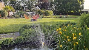 Ein Garten mit Teich, Grünflächen und Rasen.