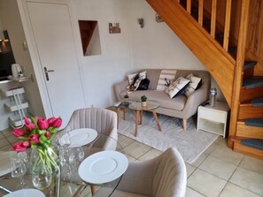 A modern living room with a sofa, coffee table, and a dining area with chairs and plates.