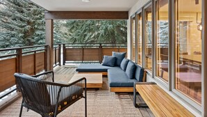 Een balkon met een bank, stoelen en een houten tafel.