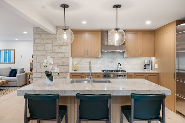 A modern kitchen with a central island, wooden cabinets, and stainless steel appliances.