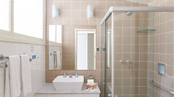 A modern bathroom with a glass-enclosed shower, a white sink, and a large mirror.