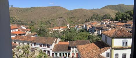 A town with terracotta-roofed buildings, a church, and hills in the background.