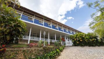 Um edifício com fachada branca, varandas azuis e um caminho de pedra que leva à entrada.