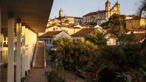 A staircase leading to a building with a clock tower, surrounded by lush greenery and palm trees. - Grande Hotel de Ouro Preto (Ouro Preto)