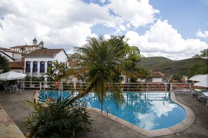 Una piscina rodeada de palmeras y edificios blancos con techos de tejas rojas.