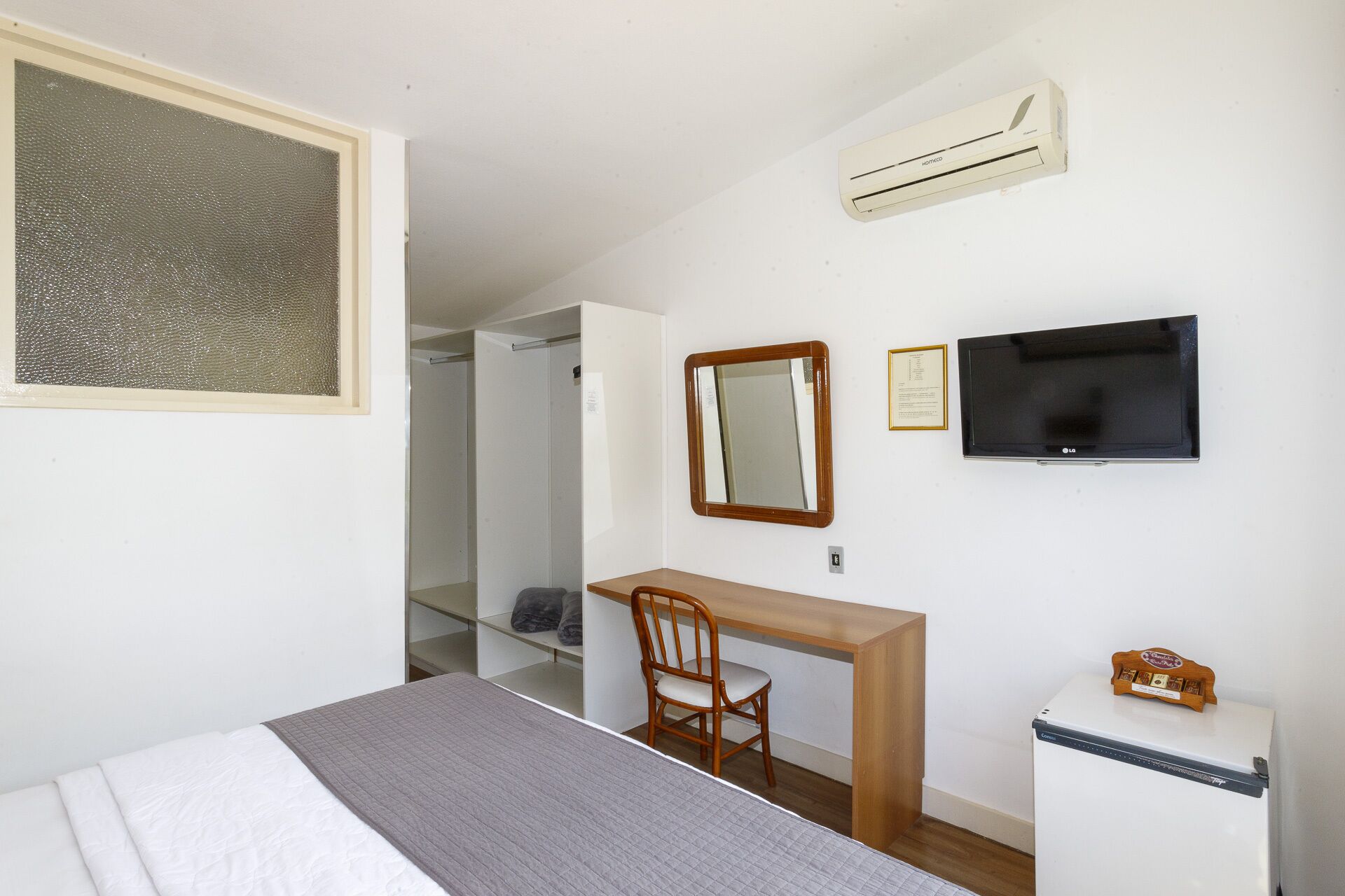 Une chambre à coucher comprenant un lit, un bureau, une chaise, une télévision et un réfrigérateur.