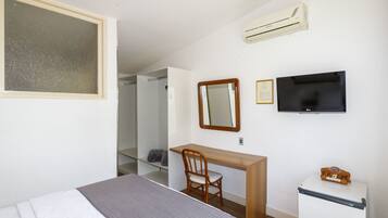 Une chambre à coucher comprenant un lit, un bureau, une chaise, une télévision et un réfrigérateur.