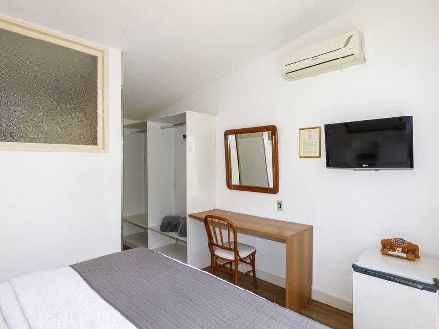 Une chambre à coucher comprenant un lit, un bureau, une chaise, une télévision et un réfrigérateur.
