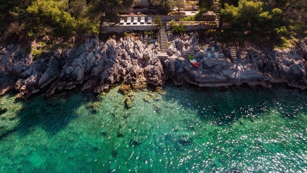 A coastal property with a stone staircase leading to a terrace, surrounded by trees and overlooking clear turquoise waters. - Holiday Home Melanie (Blato)