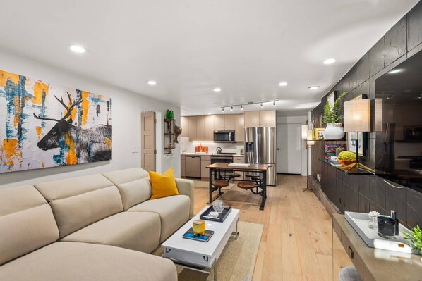 A modern living room with a sofa, coffee table, and a painting of a deer.