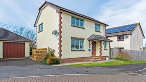A two-story residential house with a garage, a small front porch, and a solar panel on the roof. - Oceanside | Sleeps 6 |Walk to Beach & Stylish (Croyde)