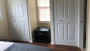 A bedroom with a bed, a nightstand, and two white doors.