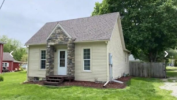 A single-story house with a stone facade, a gabled roof, and a front porch.