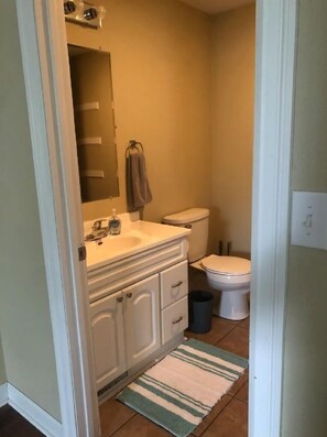A compact bathroom with a white sink, vanity, and toilet. A striped rug is on the floor. - Charming One Bedroom home in Keosauqua near shops (Keosauqua)