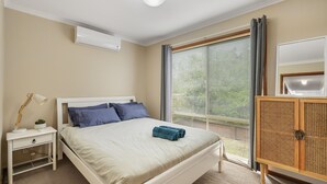 A bedroom with a bed, bedside table, lamp, and a window with blinds. - Settlement Sands Cowes (Cowes)