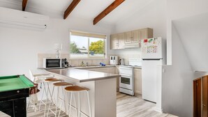 A modern kitchen with a central island, bar stools, a microwave, a kettle, and a refrigerator. - Settlement Sands Cowes (Cowes)