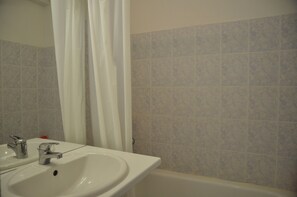 Un bagno con lavandino, specchio e tenda per la doccia.