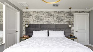 Un dormitorio con una cama grande, dos mesitas de noche y un cabecero frente a una pared con textura.