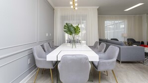Un comedor moderno con una mesa blanca, sillas tapizadas de color gris y una planta decorativa grande.
