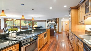 A modern kitchen with a large island, wooden cabinets, and pendant lighting. - Modern Vail Retreat | King Suite + Bunk Room • Stone Fireplace • Huge Patio (Vail)