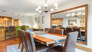 A dining area with a large wooden table, leather chairs, and a chandelier. - Modern Vail Retreat | King Suite + Bunk Room • Stone Fireplace • Huge Patio (Vail)
