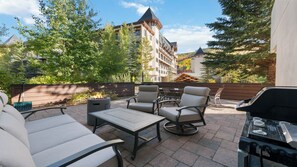 An outdoor patio with seating, a fire pit, and a grill area. - Modern Vail Retreat | King Suite + Bunk Room • Stone Fireplace • Huge Patio (Vail)