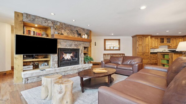 A living room with a fireplace, leather sofa, and wooden cabinets. - Modern Vail Retreat | King Suite + Bunk Room • Stone Fireplace • Huge Patio (Vail)