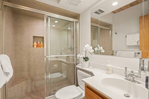Une salle de bain moderne avec une douche à parois de verre, des toilettes blanches, un meuble-lavabo avec un miroir et un évier.