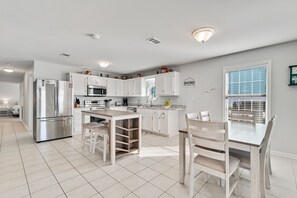 A modern kitchen with white cabinetry, stainless steel appliances, and a breakfast bar.
