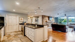 A modern kitchen with white cabinetry, a granite countertop, and a stone backsplash. - Immaculate 2BR • Stone Fireplace • Beaver Creek Views & Luxury Finishes (Vail)
