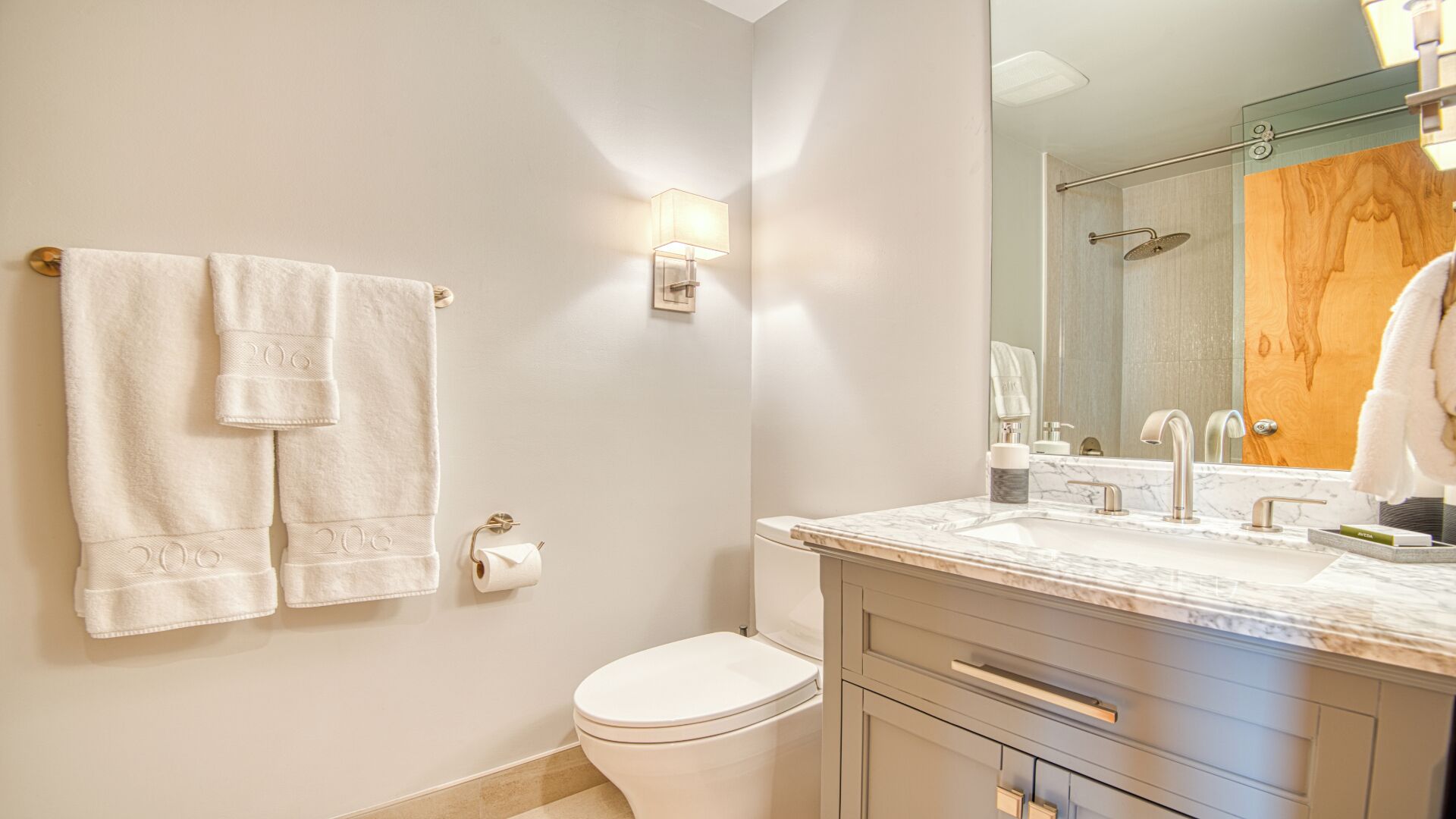 Un bagno con un WC, un lavandino con uno specchio e due asciugamani su un porta-asciugamani.