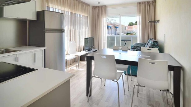 Una cucina moderna con piano cottura integrato, frigorifero e zona pranzo con tavolo e sedie.