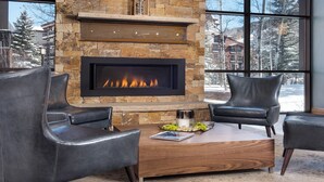 A stone fireplace with a black screen, two leather chairs, and a wooden coffee table with a magazine and a vase of greenery. - Spacious 2BR • Open Concept • Remodeled Kitchen & Baths | Flexible Sleeping (Vail)