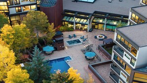 A rooftop patio with a swimming pool, outdoor seating, and a fire pit.