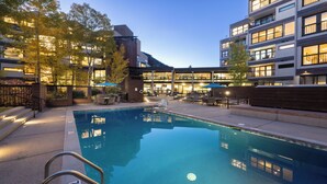 A pool area with a clear view of the pool, surrounding lounge chairs, and a building with multiple floors and balconies.