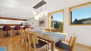 A modern dining area with a wooden table, matching chairs, and pendant lighting. - Spacious 3BR • Stone Fireplace • Family-Friendly Vail Mountain Retreat (Vail)