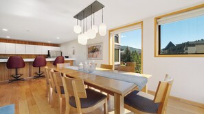 A modern dining area with a wooden table, matching chairs, and pendant lighting.