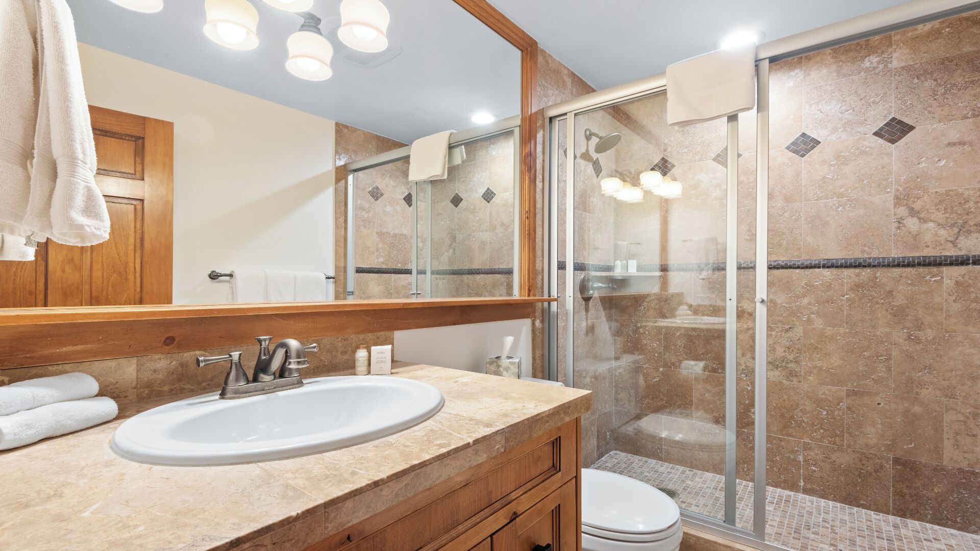 A bathroom with a sink, mirror, shower, and toilet.