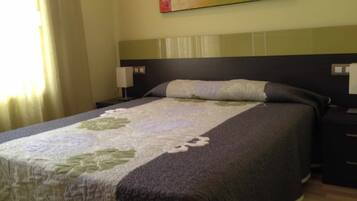 A neatly made bed with a floral-patterned bedspread, a dark headboard, and two bedside lamps.