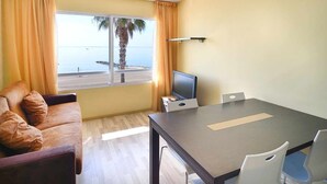 A room with a sofa, a TV, a table, and a view of the sea. - ORNIS "Becassina": 1 bedroom+sofa-bed 2/4 pers windows sea view (Sant Carles De La Rapita)