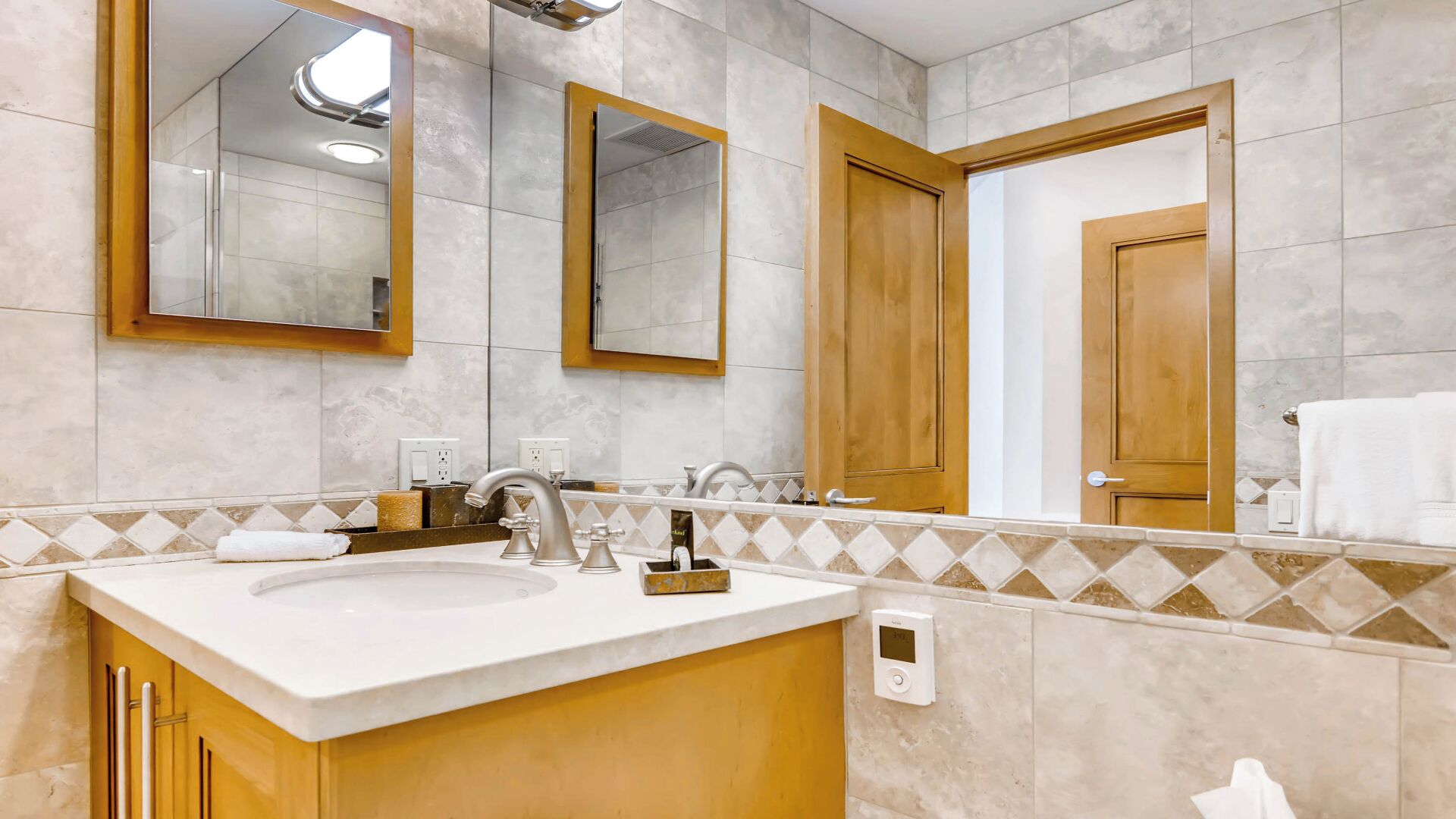 Casa de banho com lavatório, espelhos e porta-toalhas.
