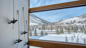 Quarto com uma grande janela com vista para uma paisagem nevada de montanha.