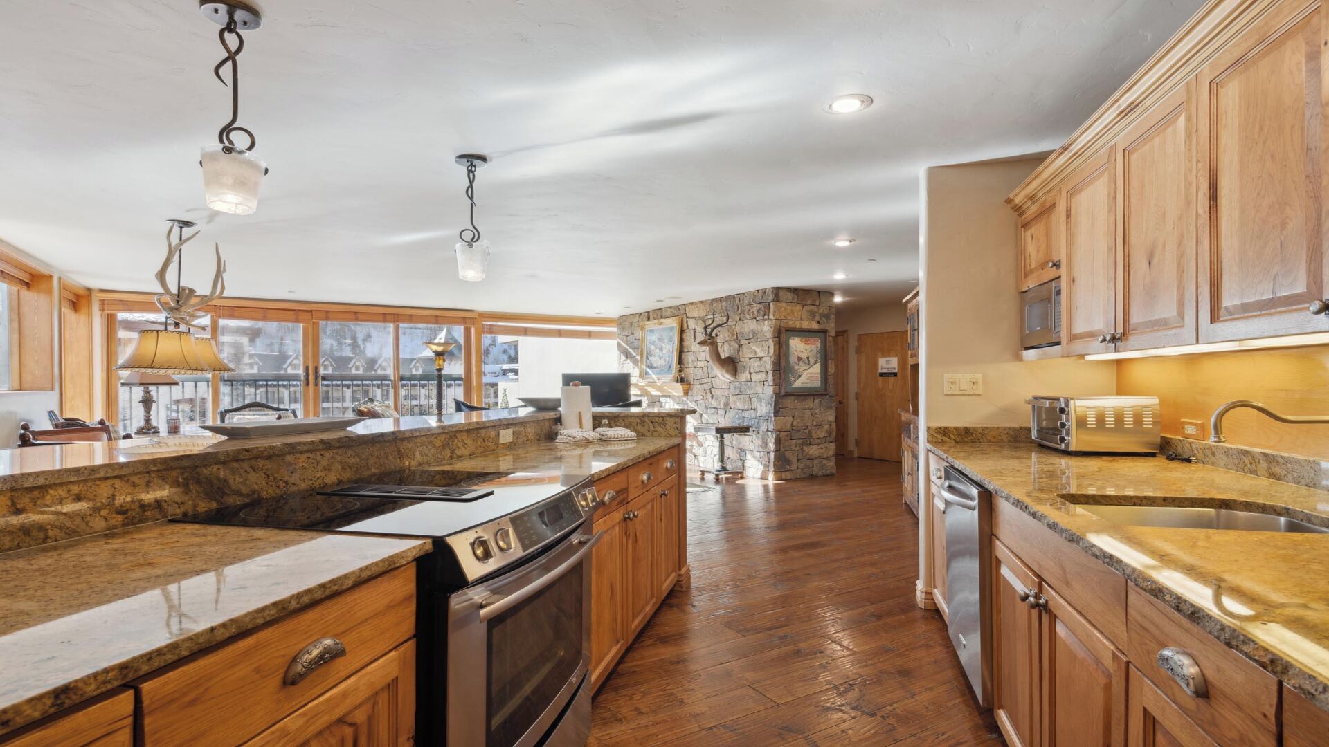 Una cocina amplia con encimeras de granito, armarios de madera, horno empotrado y una pared decorativa de piedra.