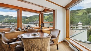 Ein Zimmer mit großem Fenster, einem runden Tisch, Ledersesseln und einer Statue.