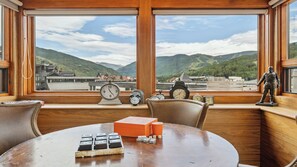 A room with a large window, wooden furniture, a table with playing cards, and a statue.