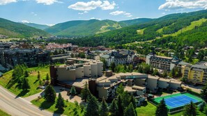 A mountainous town with a mix of modern and traditional buildings, a prominent road, and a tennis court.