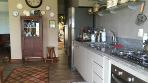 A kitchen with a built-in stove, a refrigerator, and a wooden cabinet with glass doors. - Brotas Shangri-lá with 3 suites, pool and stunning views! (Caju)