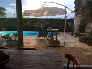 A patio area with a pool, outdoor furniture, and potted plants. - Brotas Shangri-lá with 3 suites, pool and stunning views! (Caju)