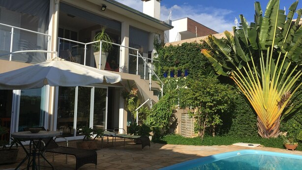 A poolside area with a lounge chair, a table, and a covered seating area. - Brotas Shangri-lá with 3 suites, pool and stunning views! (Caju)